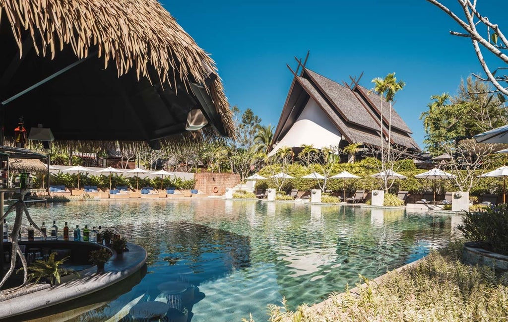 Contemporary beachfront resort with infinity pool, surrounded by tropical gardens, facing pristine Mai Khao Beach at sunset