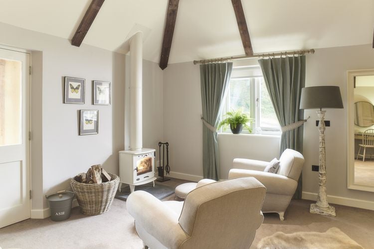 Spacious modern suite with panoramic lake views, elegant wood furnishings, plush king bed, and floor-to-ceiling windows at The Fish Hotel in the Cotswolds