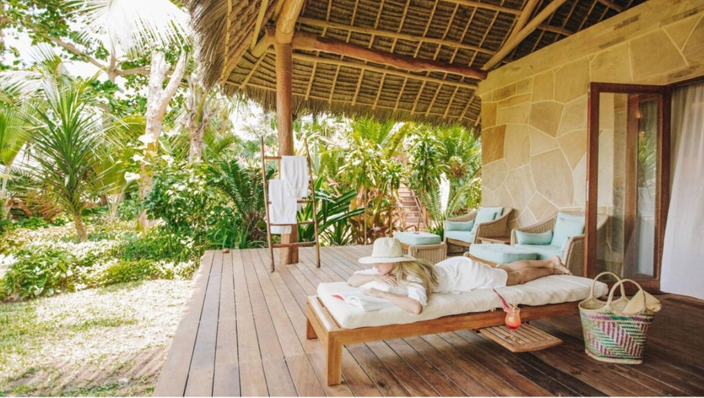 Luxurious beachfront resort with infinity pool overlooking white sandy beach, swaying palm trees and turquoise Indian Ocean waters