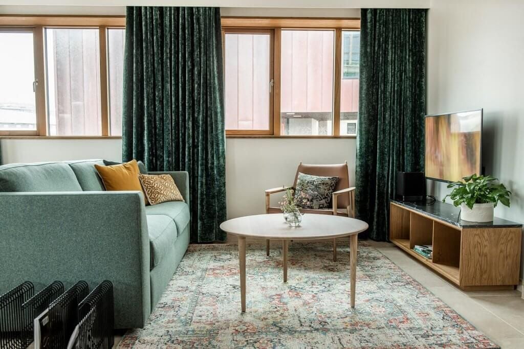 Luxurious superior suite with modern Nordic design, featuring minimalist decor, plush king bed, large windows overlooking urban Norwegian landscape