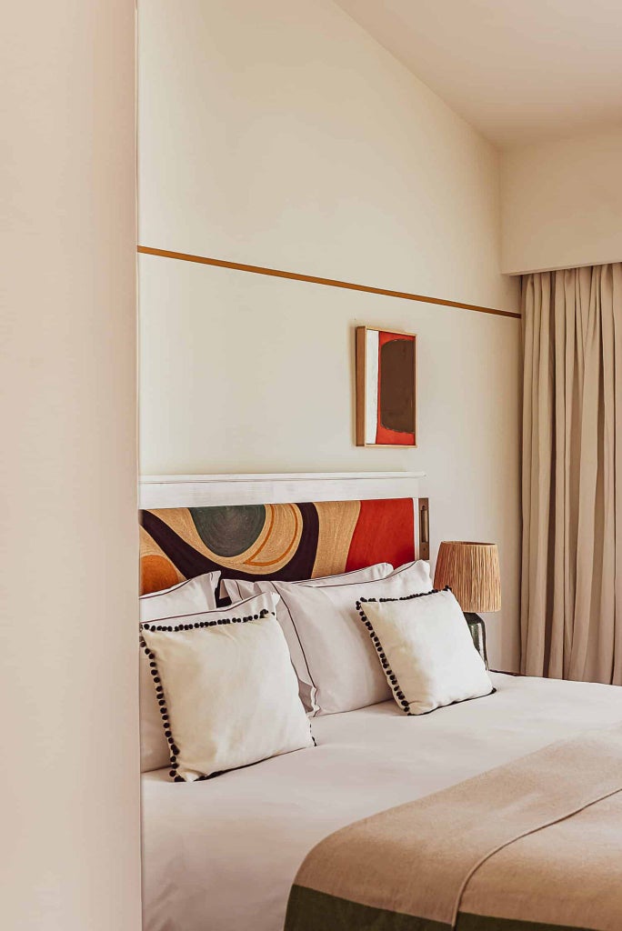 Elegant deluxe hotel room with crisp white linens, soft neutral tones, plush bedding, and chic French Riviera-inspired decor at Lou Pinet luxury resort