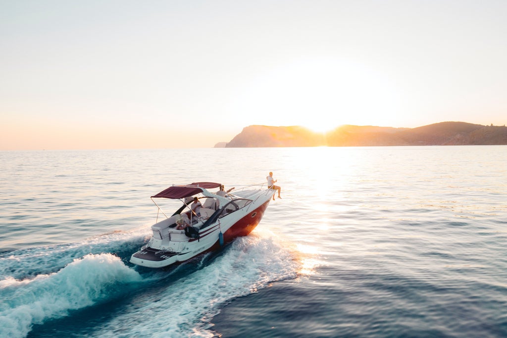 Luxurious white sailboat anchored in crystal-clear Mediterranean waters near Taormina's coastline, with Mount Etna in the background