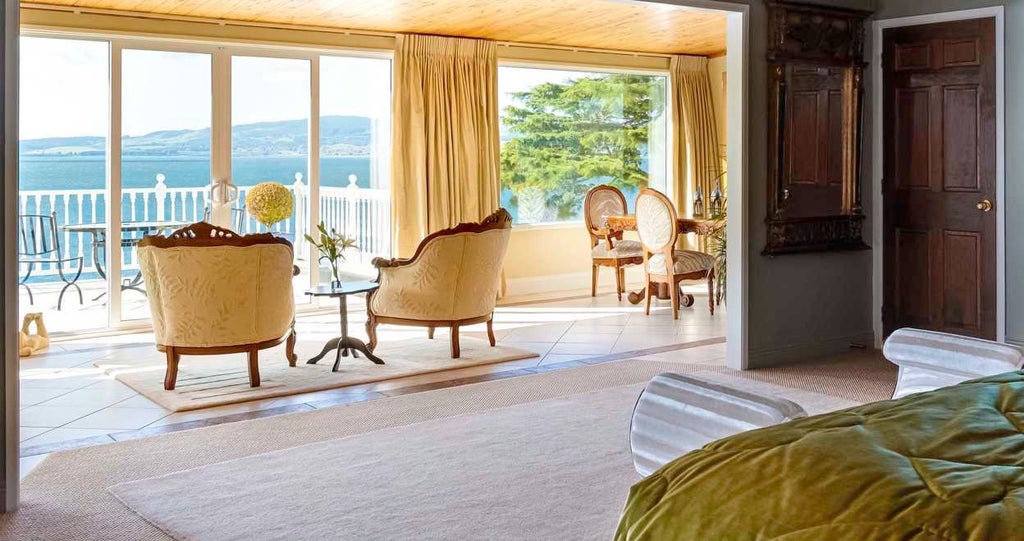 Luxurious main suite overlooking stunning New Zealand landscape with floor-to-ceiling windows, elegant contemporary design, and panoramic scenery of coastal waters