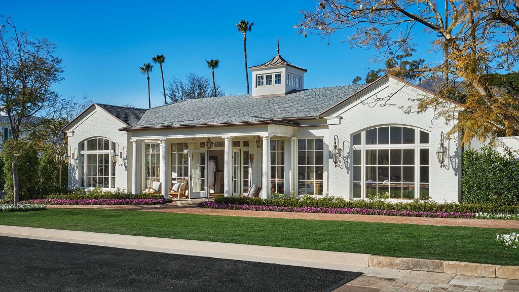 Luxurious beachfront resort with pristine white buildings, lush green landscaping, and azure ocean views at a high-end coastal property