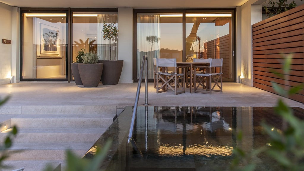 Elegant poolside suite with private infinity pool overlooking Aegean Sea, featuring modern furnishings and lush Mediterranean gardens