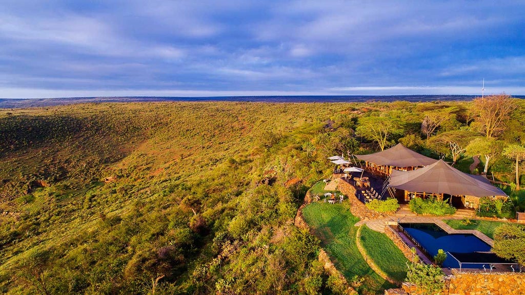 Luxury tented camp overlooking dramatic Kenyan wilderness with canvas suites, wooden decks, and sweeping views of rugged landscape at golden hour