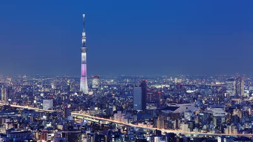 Elegant modern skyscraper hotel in Tokyo with floor-to-ceiling windows offering panoramic city views, illuminated against twilight sky