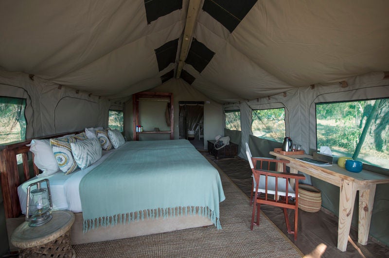 Safari lodge's elevated deck overlooking the Okavango Delta, with plush outdoor seating and lanterns beneath a thatched roof canopy