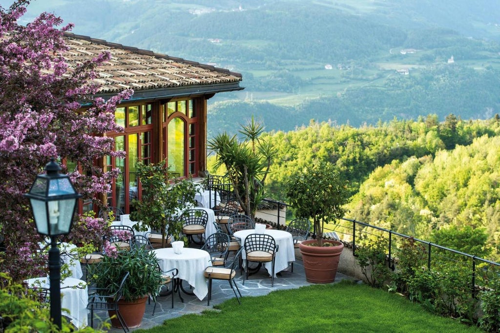 Elegant stone-built hotel nestled in Italian Alps with traditional architecture, panoramic mountain views, and manicured gardens