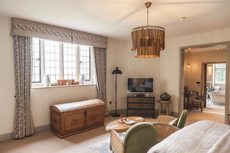 Elegant chestnut-toned hotel room at Foxhill Manor with plush bedding, antique furniture, and soft natural lighting casting a warm ambiance