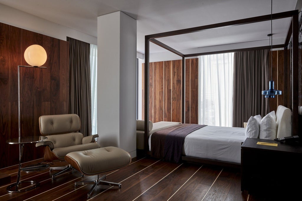 Modern minimalist hotel room with white walls, sleek wooden furnishings, and floor-to-ceiling windows overlooking a vibrant urban landscape in Spain's Sir Joan Hotel.