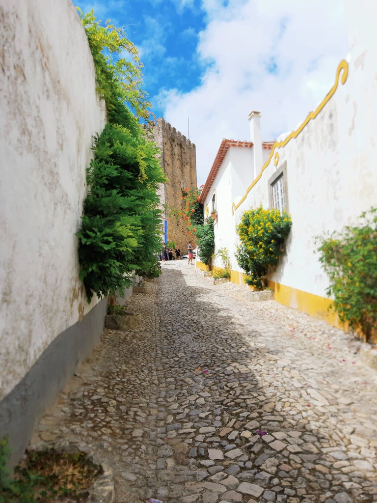 Medieval hillside town of Obidos, Portugal with whitewashed buildings, cobblestone streets and ancient castle walls overlooking terracotta roofs