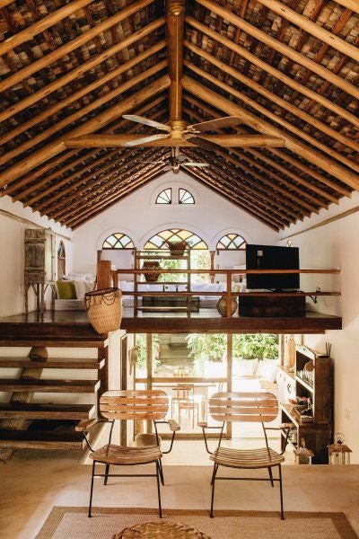 Rustic-chic Brazilian hotel room with wooden furnishings, plush white bedding, and traditional architectural details in warm, earthy tones at UXUA Casa Hotel and Spa