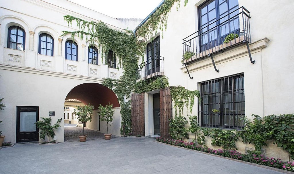 Historic Spanish palace hotel with elegant stone archways and balconies surrounding a tranquil courtyard with palm trees and marble fountain