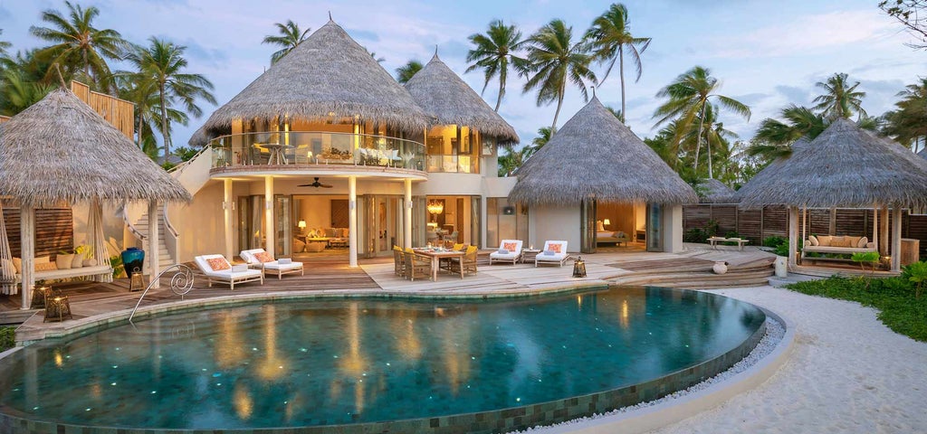 Overwater luxury villa with spiral staircase to ocean, glass floor panels, infinity pool and sunset views in the Maldives