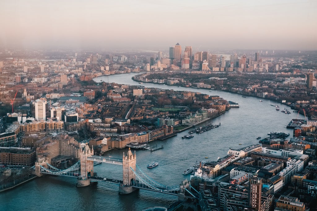 Iconic Tower Bridge spans the River Thames at sunset, with historic riverfront buildings and glittering city lights reflecting in calm waters