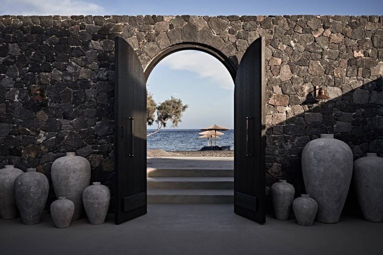 Luxurious Mediterranean suite at Istoria Hotel overlooking Santorini's caldera, featuring traditional stonework and private plunge pool