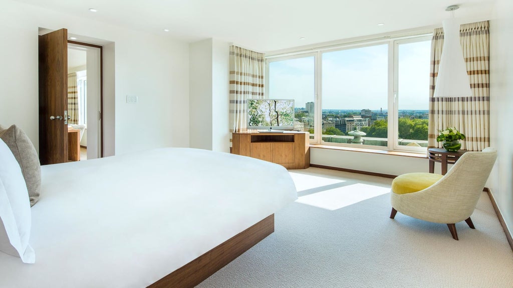Luxurious COMO Suite with plush king bed, elegant contemporary design, floor-to-ceiling windows overlooking London cityscape, soft neutral color palette