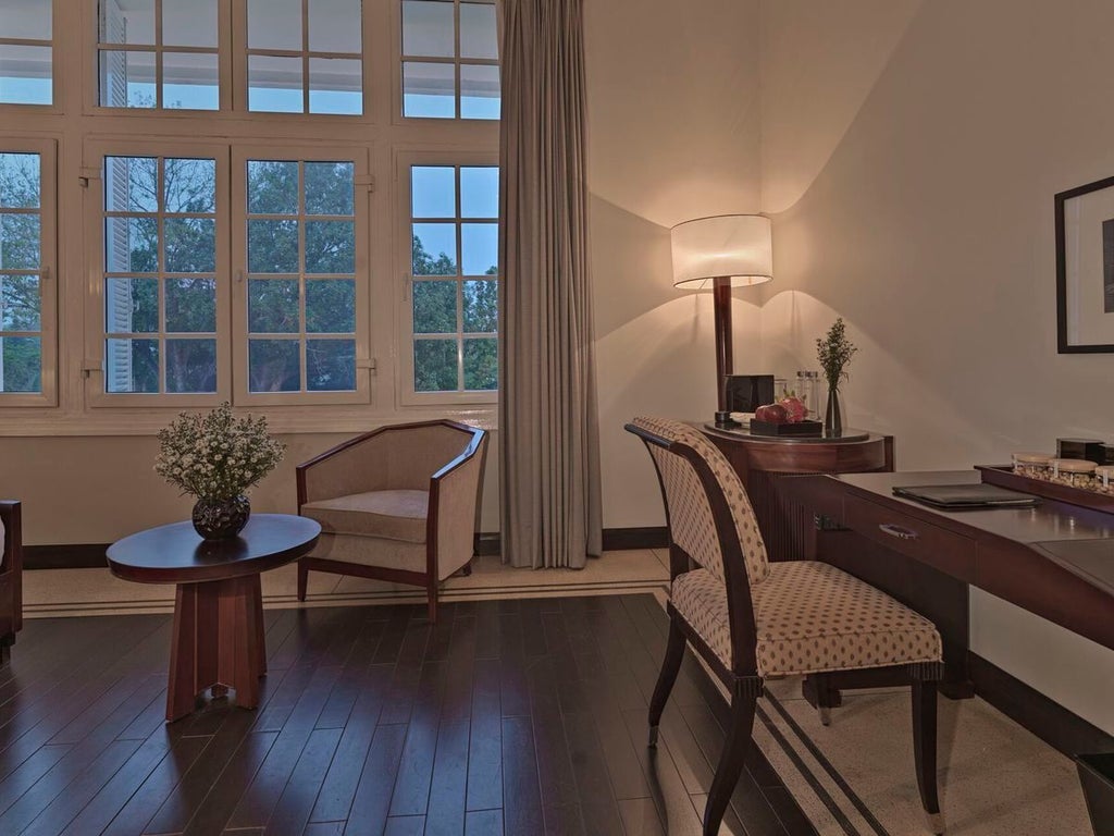 Elegant Deluxe Colonial room at Azerai La Residence, Hue, featuring pristine white linens, French-inspired decor, and rich wooden furnishings with river view