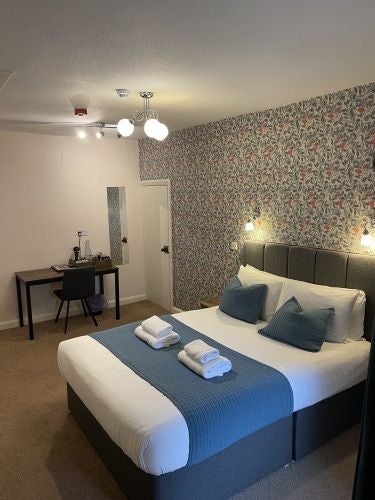 Rustic-chic hotel room at The Wheatsheaf Inn, featuring exposed wooden beams, plush white bedding, and traditional British countryside elegance