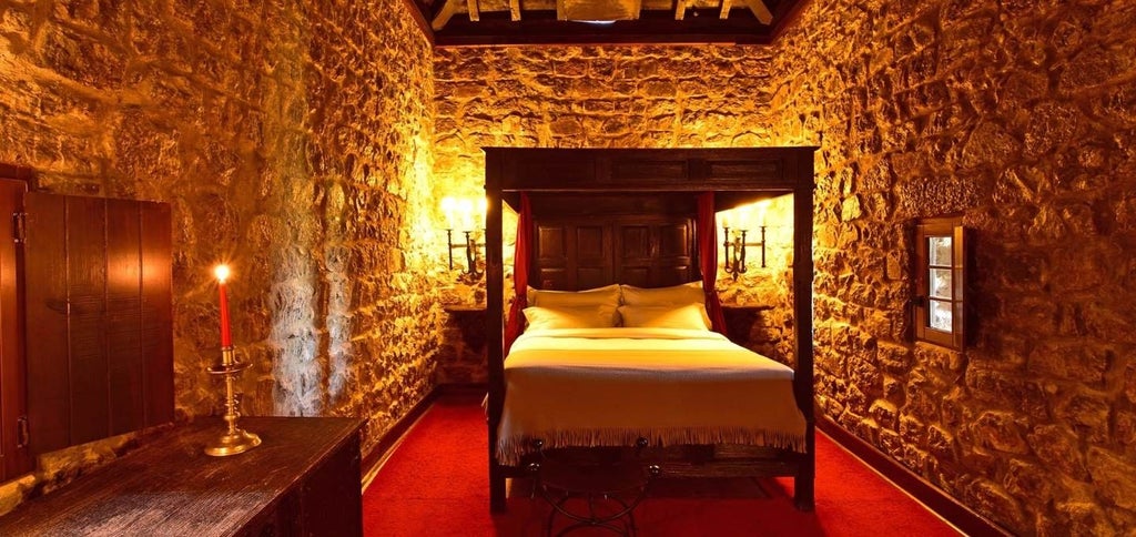 Medieval Portuguese castle-hotel with stone walls and turrets overlooking Obidos village, set against a clear blue sky at sunset