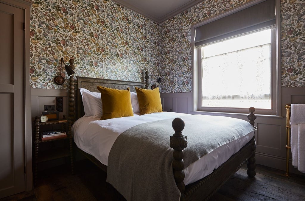 Cozy, rustic hotel room at The Pig in South Downs with plush bedding, vintage furnishings, and soft natural light filtering through large windows