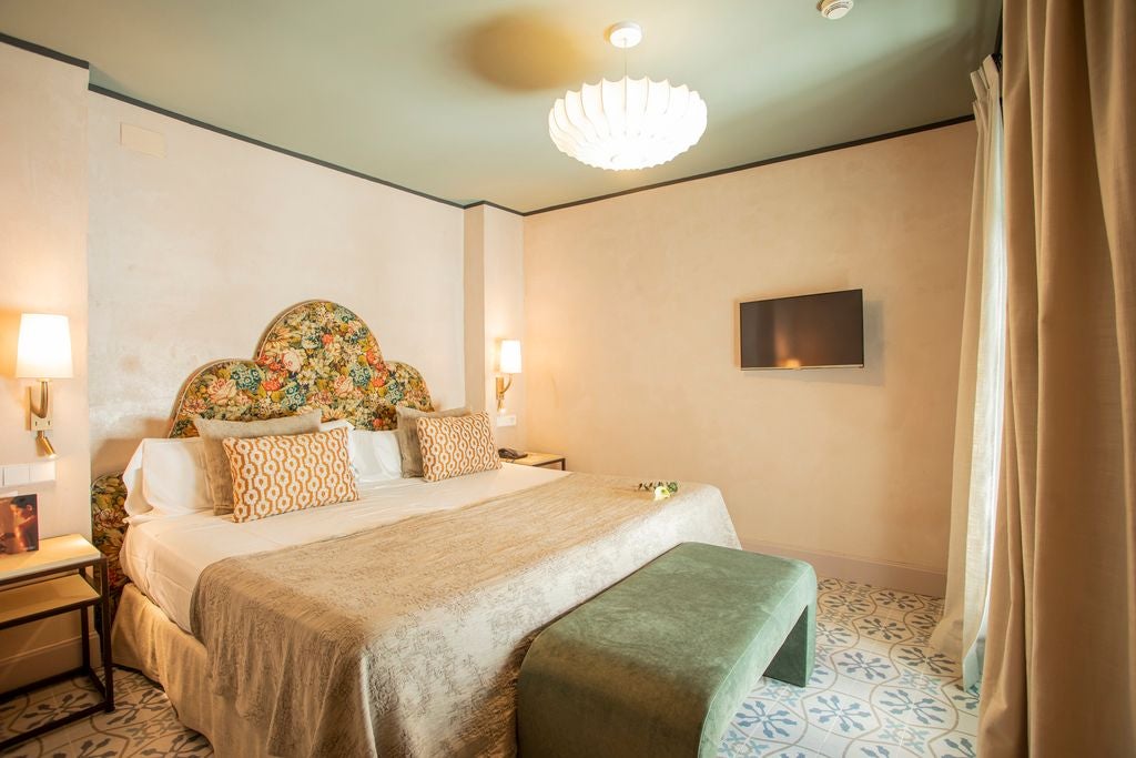 Elegant white-walled suite in historic Spanish hotel with traditional wooden furniture, arched windows, and luxurious minimalist design