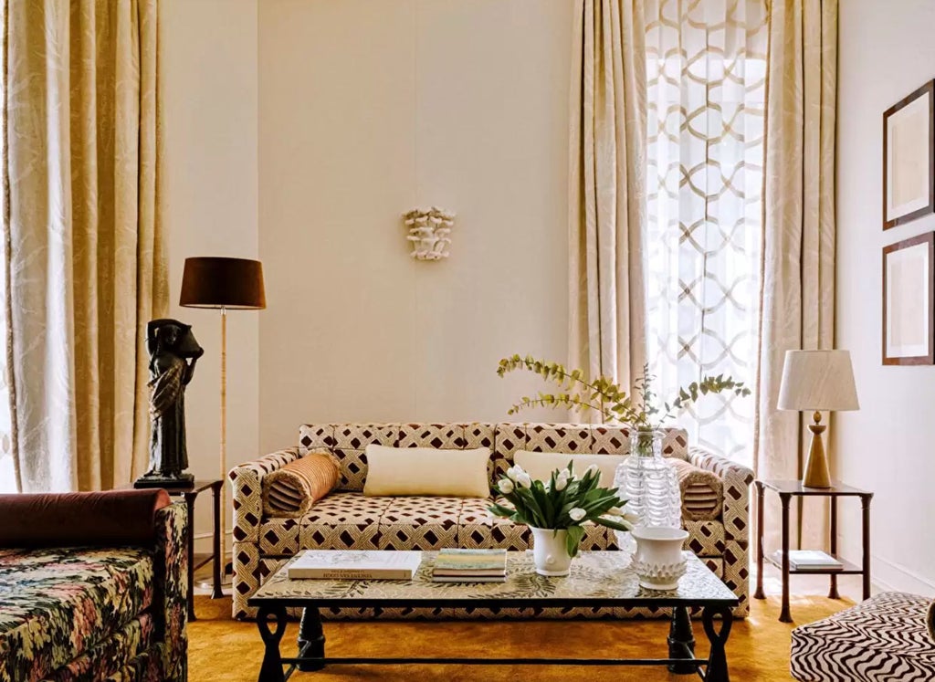 Opulent Parisian suite with crystal chandelier, antique furnishings, gold-framed mirrors and elegant striped wallpaper in cream and red