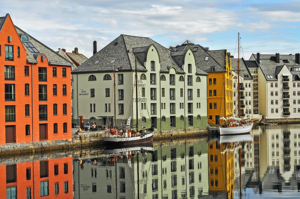 Historic town of Ålesund with Art Nouveau buildings nestled between mountains and fjords, colorful facades reflecting in calm harbor waters