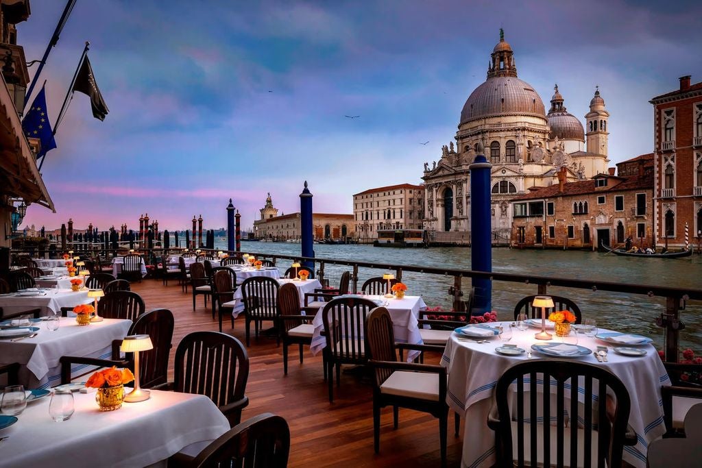 Ornate Venetian Gothic façade of The Gritti Palace hotel with marble columns and arched windows overlooking the Grand Canal at sunset