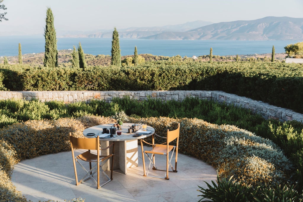 Luxurious Amanzoe resort pavilions nestled on Greek hillside, featuring infinity pools and classical columns against Mediterranean views