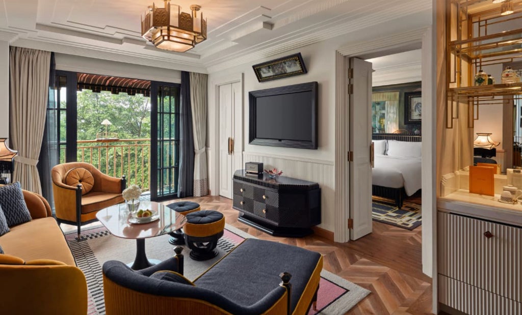 Opulent Premier Suite with ornate gold accents, plush king bed, marble bathroom and floor-to-ceiling windows overlooking Hanoi cityscape