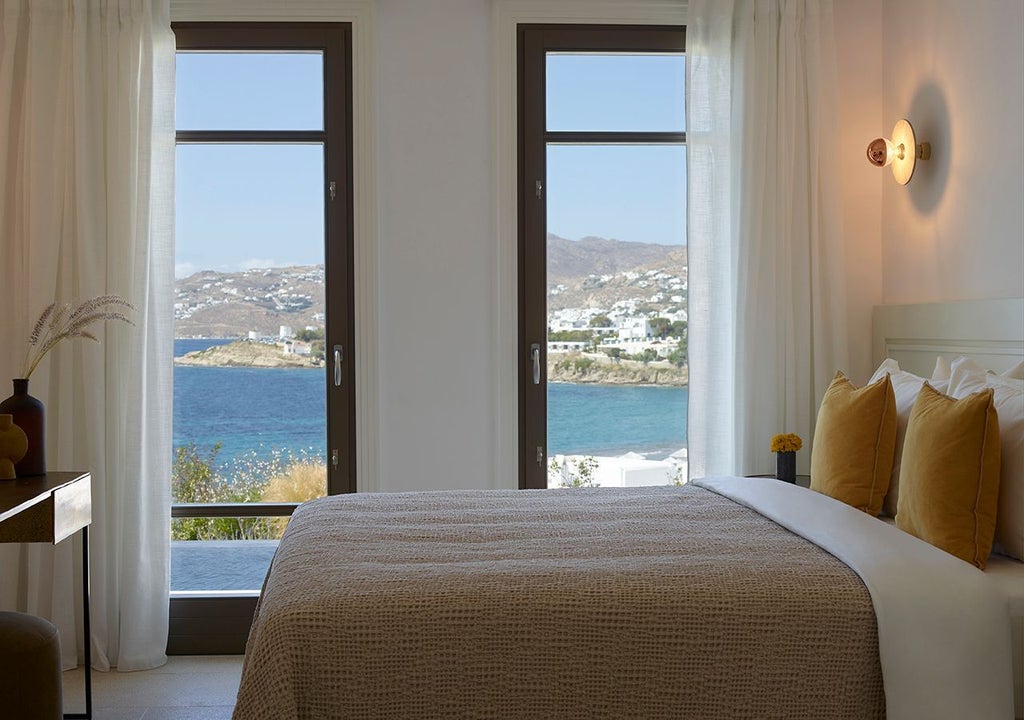 Luxurious Mykonos hotel lounge suite with panoramic sea view, featuring sleek modern design and a private heated plunge pool at sunset