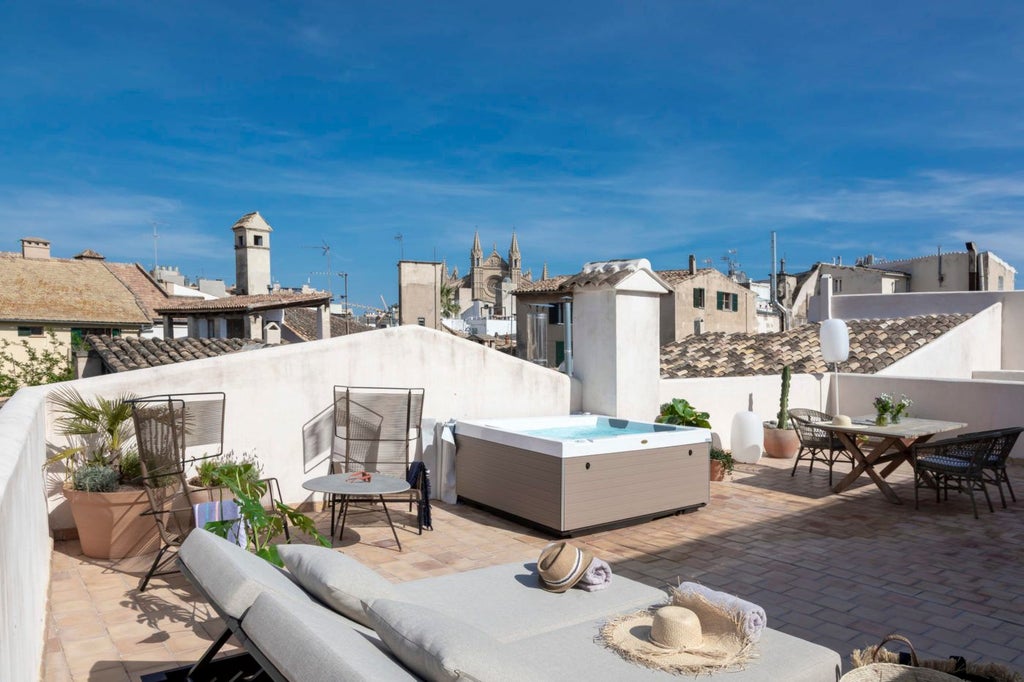 Elegant sky suite with plush white bedding, arched windows overlooking lush garden, antique wooden furniture, and soft natural light in historic Spanish hotel