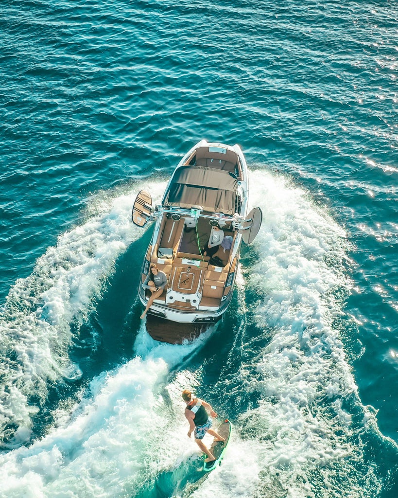 Luxury yacht sails between scenic Croatian islands at sunset, with crystal-clear turquoise waters and rugged coastline in background