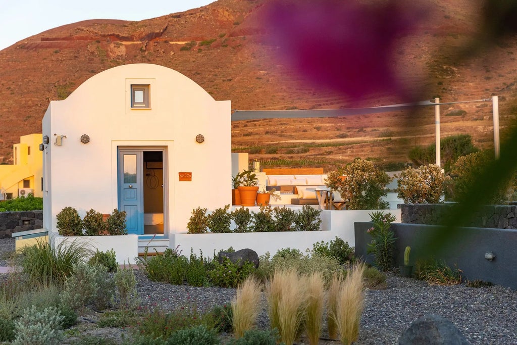 Luxurious whitewashed Greek villa with blue shutters overlooking Aegean Sea, featuring stone walls, elegant terraces, and vibrant bougainvillea flowers