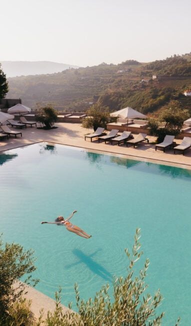 Elegant stone-facade hotel nestled in lush Portuguese landscape, featuring modern architectural design with classic regional charm near scenic mountainous terrain