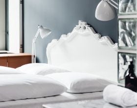 Elegant Vienna hotel dormitory with wooden bunk beds, warm lighting, vintage furnishings, and plush white linens in a refined shared sleeping space