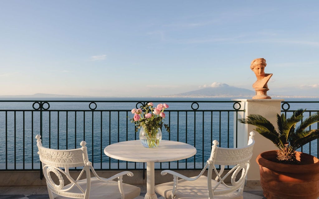 Luxurious cliff-side hotel overlooking the azure waters of Sorrento, with elegant white facade, lush Mediterranean gardens, and panoramic Tyrrhenian Sea views