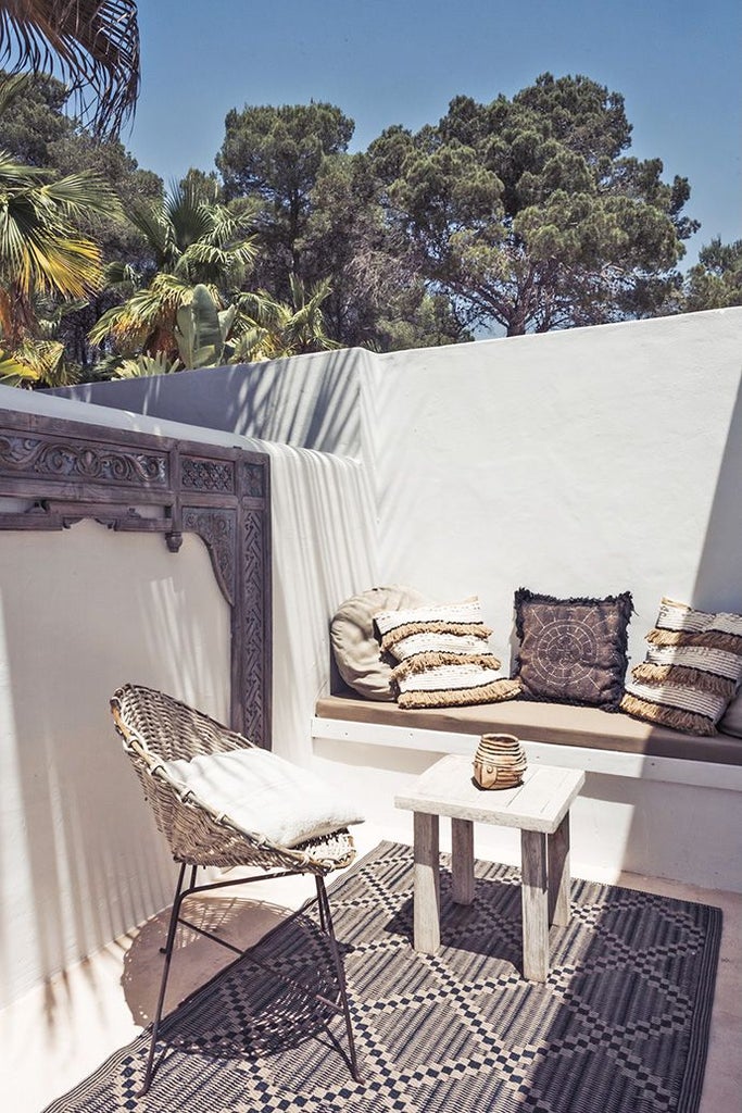 Minimalist white bedroom with clean lines, plush bedding, and large window revealing scenic Ibiza landscape, embodying serene contemporary luxury design