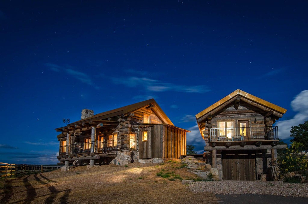 Rustic wooden lodge nestled against dramatic red rock cliffs of scenset national park, golden sunset light illuminating expansive ranch landscape