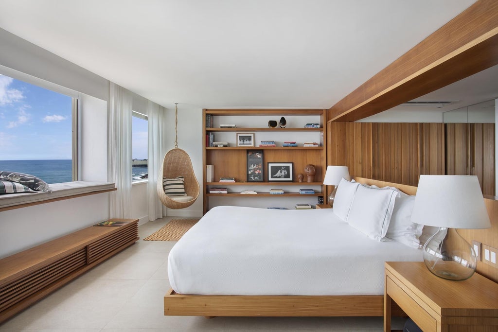 Sleek modern hotel room at Janeiro Hotel with minimalist design, floor-to-ceiling windows overlooking Brazilian coastline, elegant neutral tones and contemporary furnishings