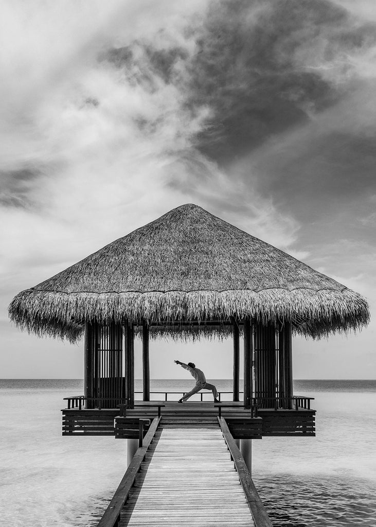 Modern overwater villa with private infinity pool extending over crystal-clear turquoise lagoon, surrounded by palm trees at sunset