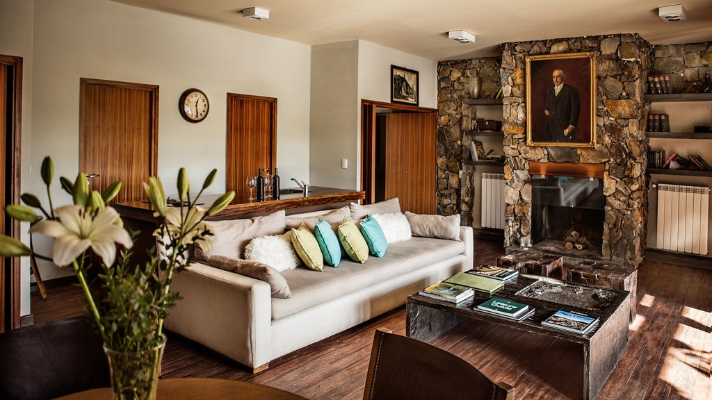 Luxurious stone lodge nestled in Mendoza vineyards with snow-capped Andes mountains in background, private terrace at sunset