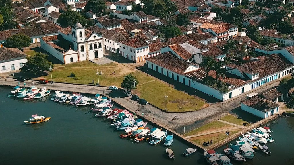 Luxurious turquoise-accented boutique hotel with colonial architecture, elegant white walls, and lush tropical garden in picturesque Brazilian setting