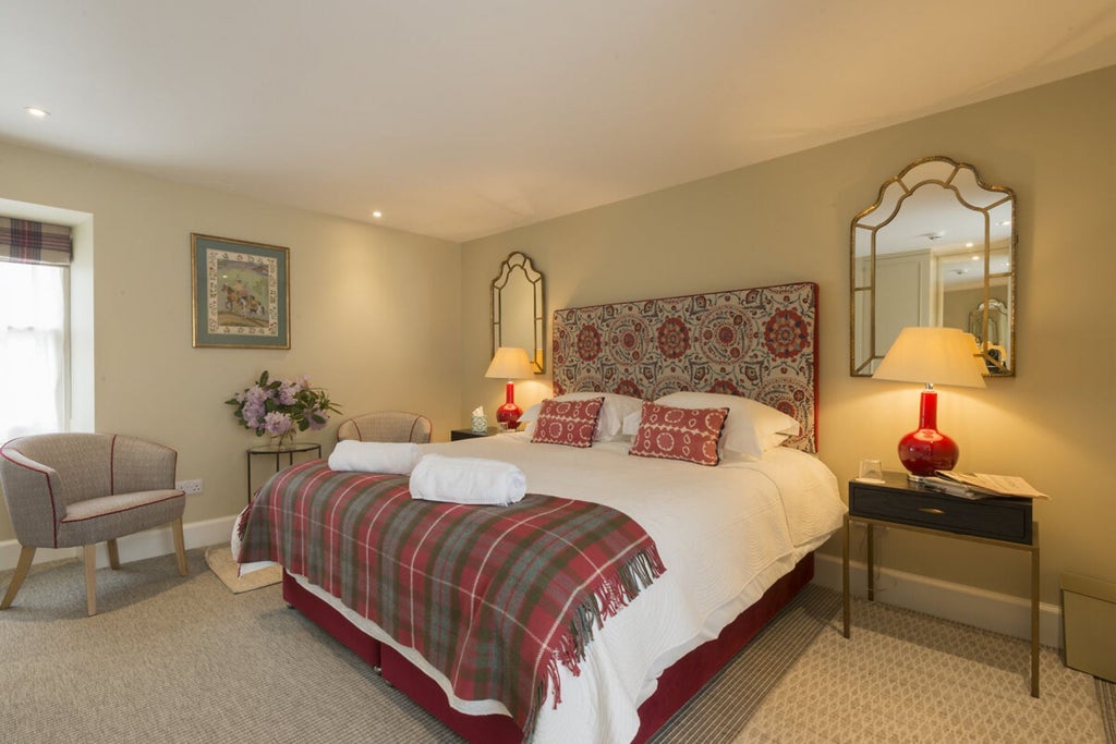 Elegant Scottish countryside bedroom with plush white bedding, tartan accents, and soft natural light streaming through vintage windows at Newhall Mains