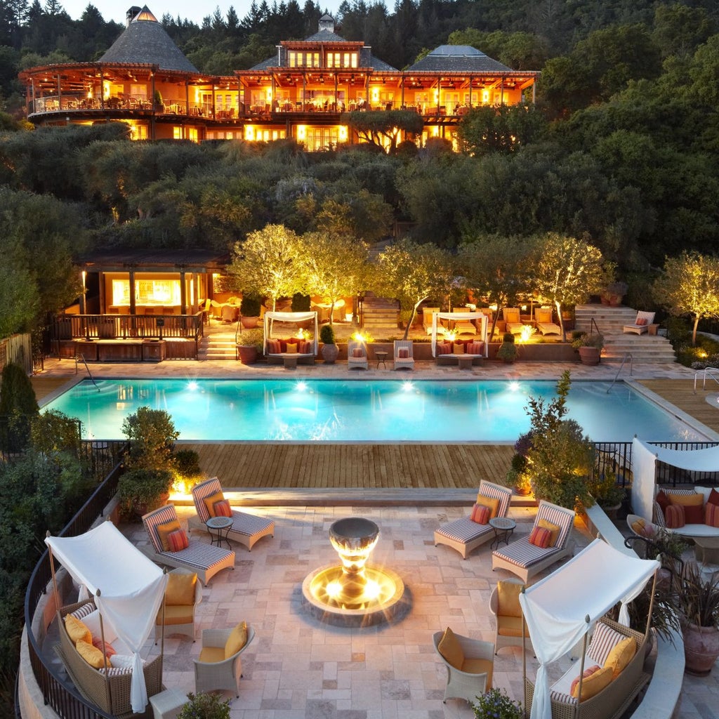 Upscale mountain resort with infinity pool overlooking Napa Valley vineyards at sunset, Mediterranean-style architecture and palm trees