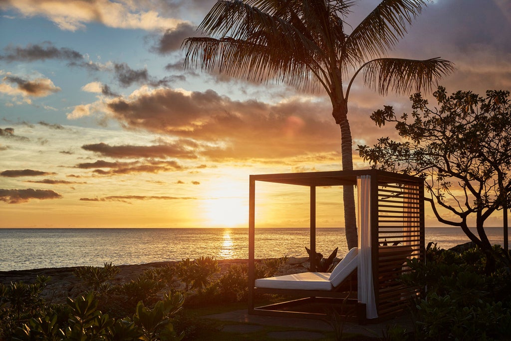 Pristine oceanfront luxury resort with infinity pools cascading toward Pacific, surrounded by swaying palms and manicured gardens