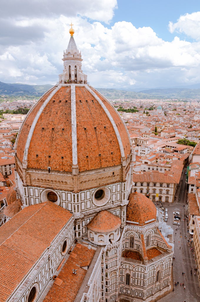 Renaissance architecture of Florence's historic center with iconic Duomo cathedral dome rising above terracotta rooftops at golden hour