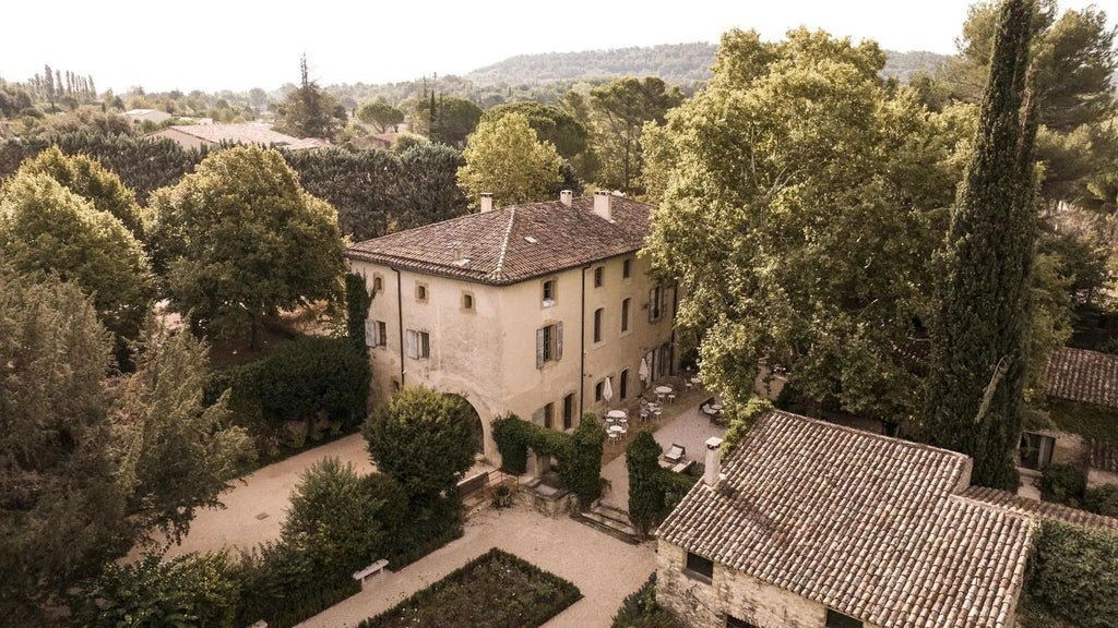 Elegant stone facade of Le Galinier hotel in Provence, with terracotta roof tiles, lush greenery, and warm Mediterranean sunlight